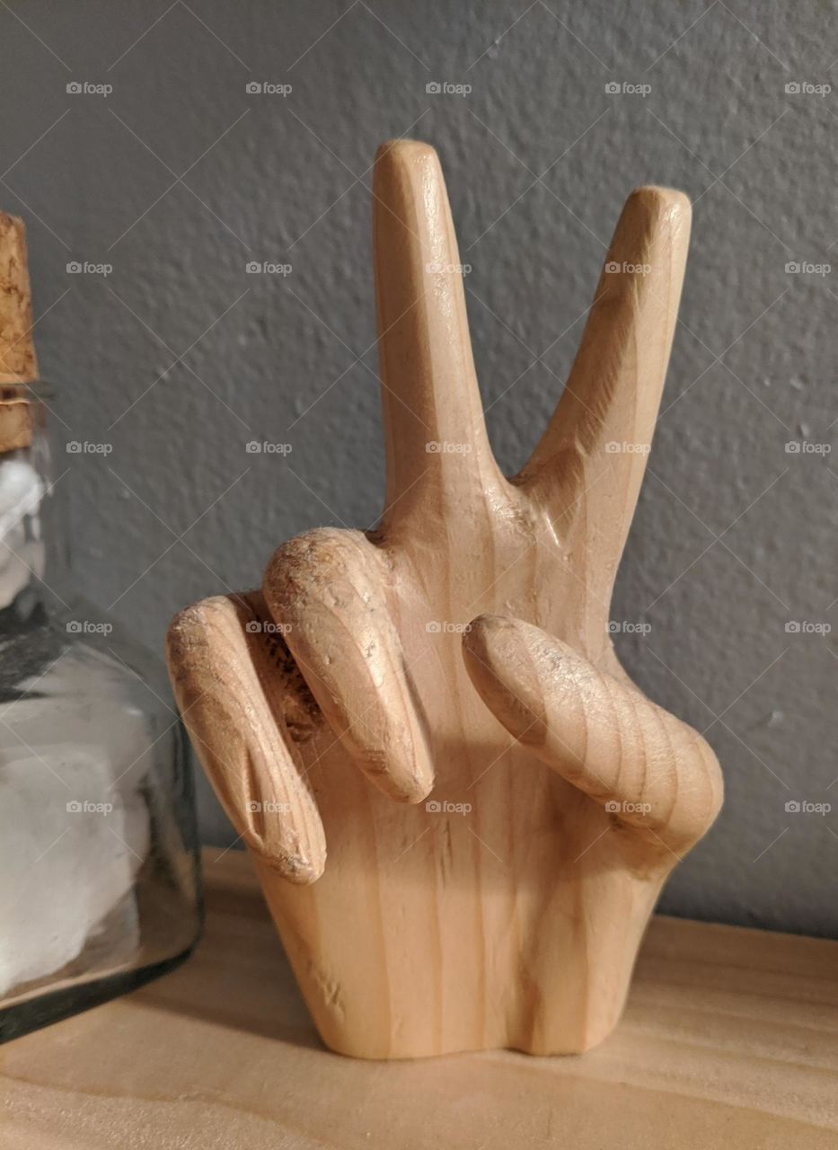 wooden peace sign hand sitting on shelf all you need is love