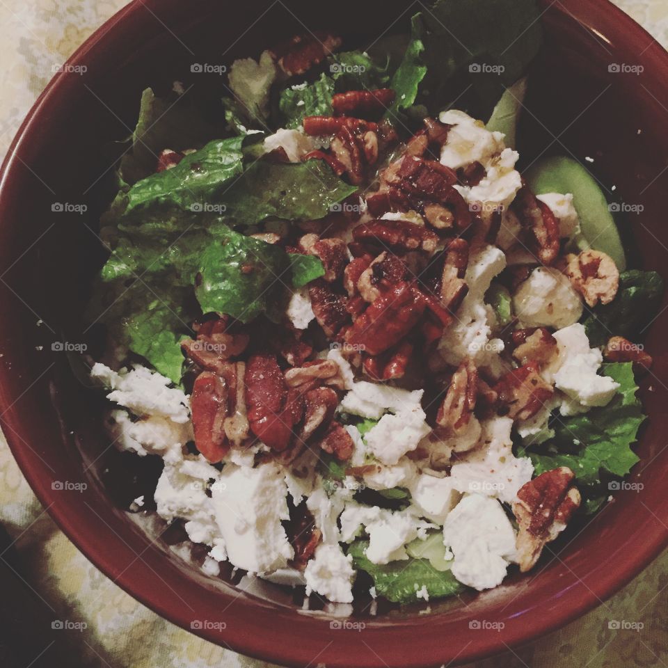 Spinach salad topped with walnuts, honey goat cheese and sweet greek dressing