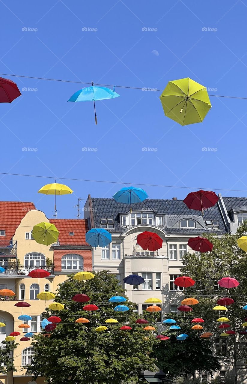 Umbrellas hanging over a Berlin street with the white moon in the sky