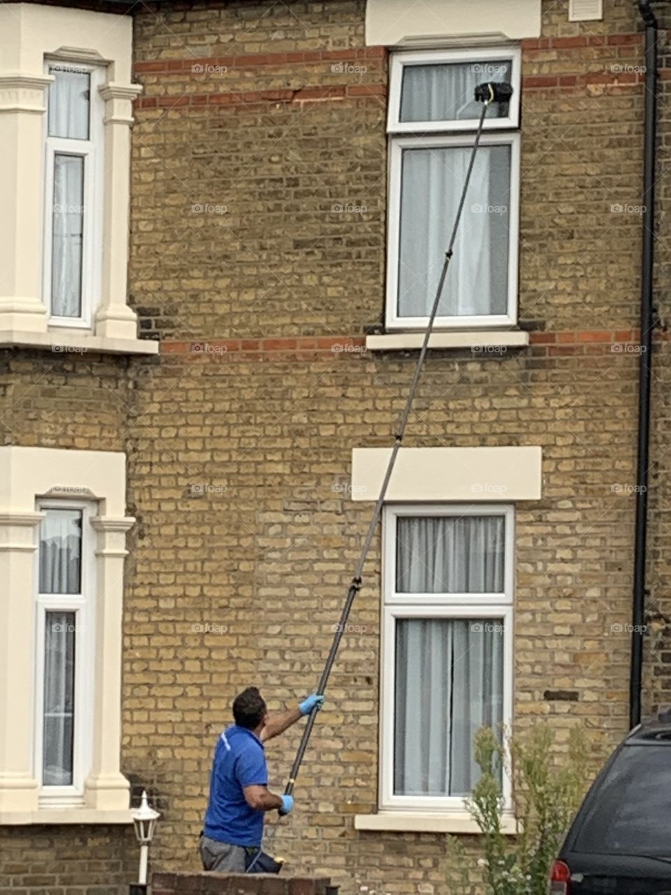 Mobile window cleaner cleaning windows with extended scrubber dispensing water 