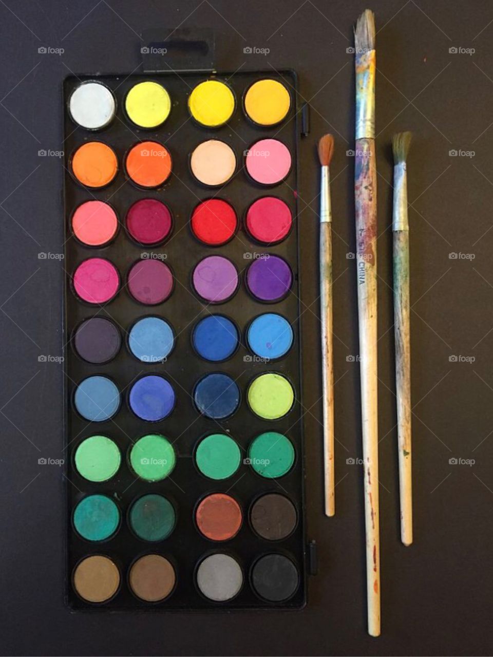 Colorful paint palette and paint brushes on black