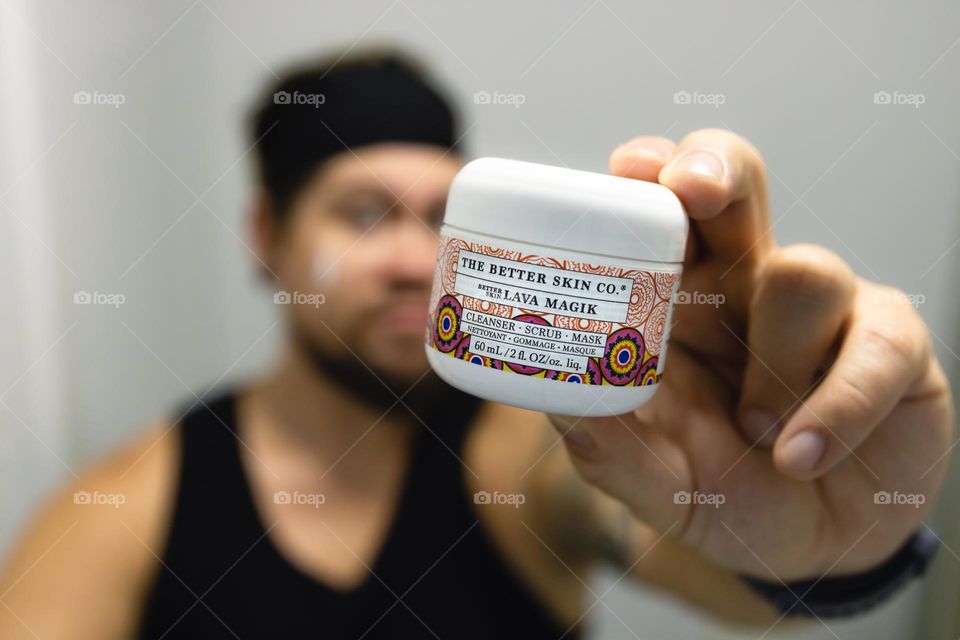 Young man holding a Lava Magik scrub container in a bathroom scene. Shallow depth of field portrait