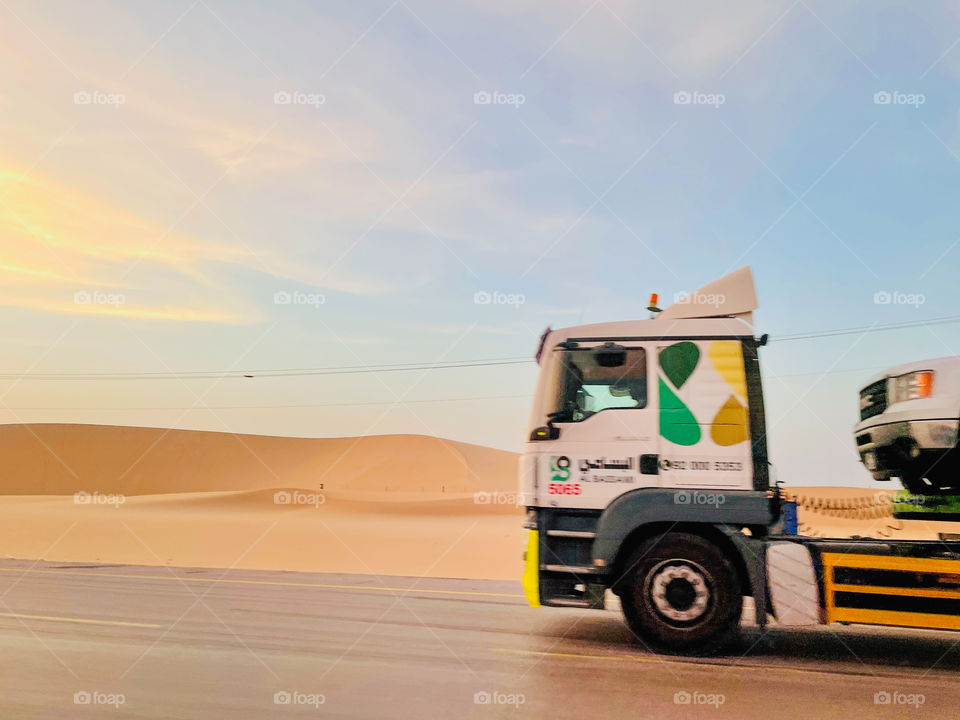 A truck on the road with beautiful sky and desert 