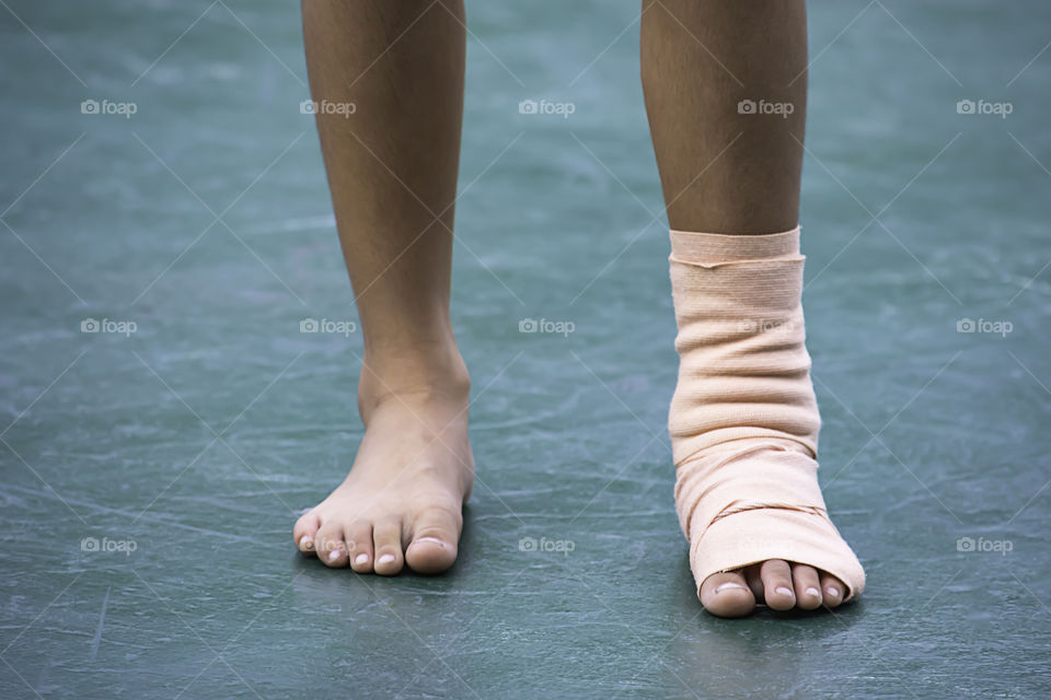 The  gauze bandages around the Ankle boy and leg swelling from inflammation On a green background.