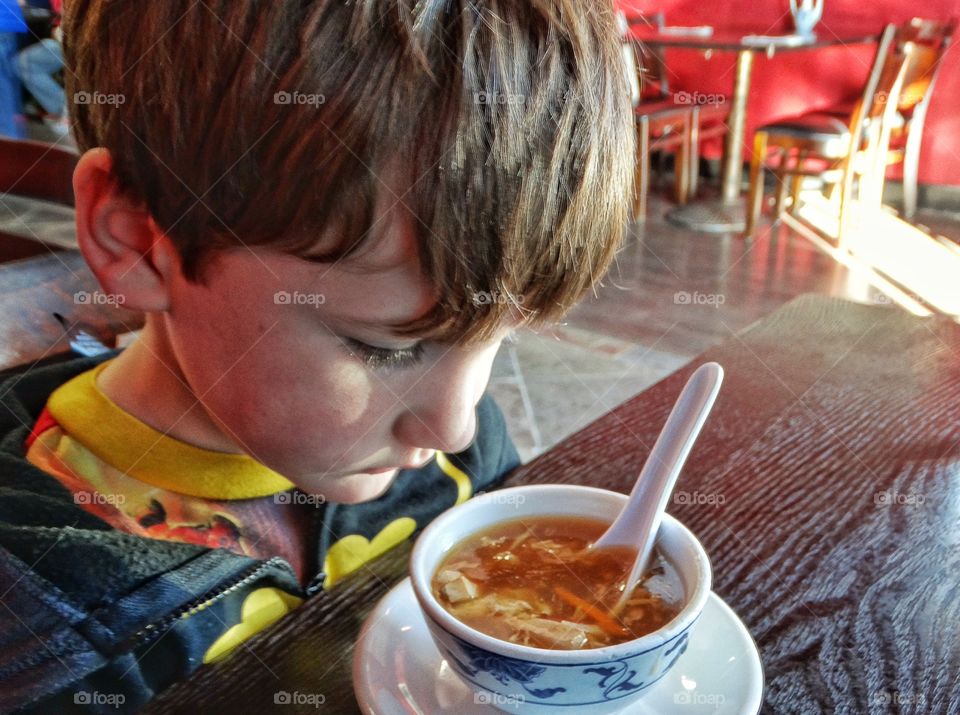 Close-up of a boy looking at soup in bowl