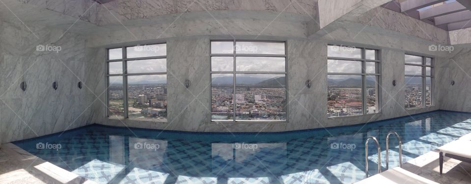 panoramic view of a swimming pool on high floor above the city