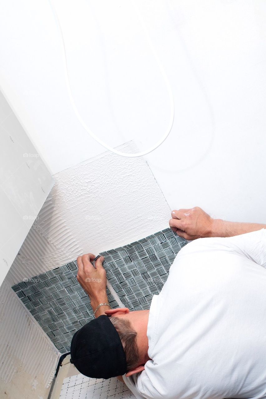 Man setting up mosaic tiles in kitchen