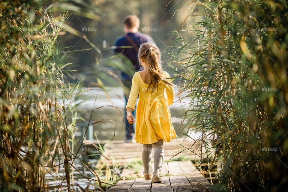 Little girl playing near lake at autumn day 