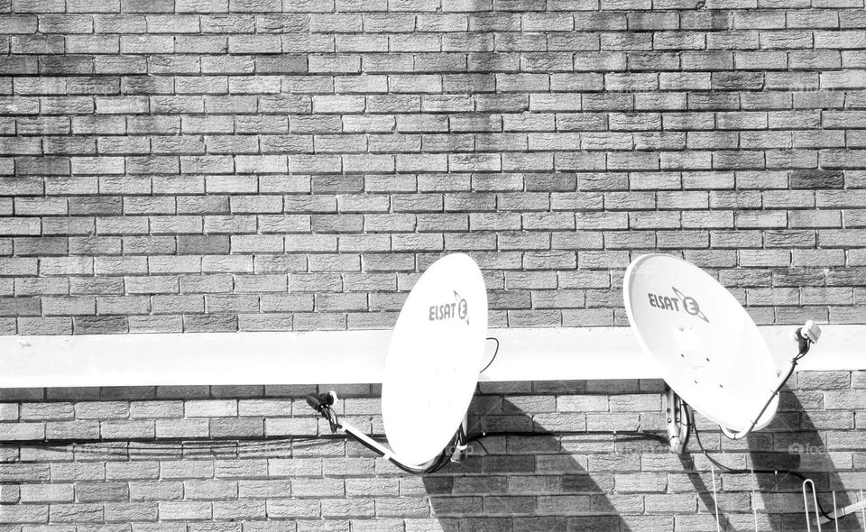 two satellite dishes on the side of a wall.