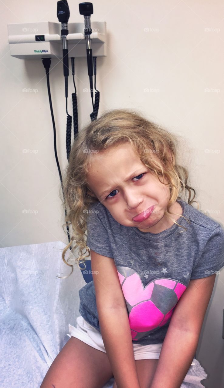 Little girl in hospital and otoscopes hanging on wall