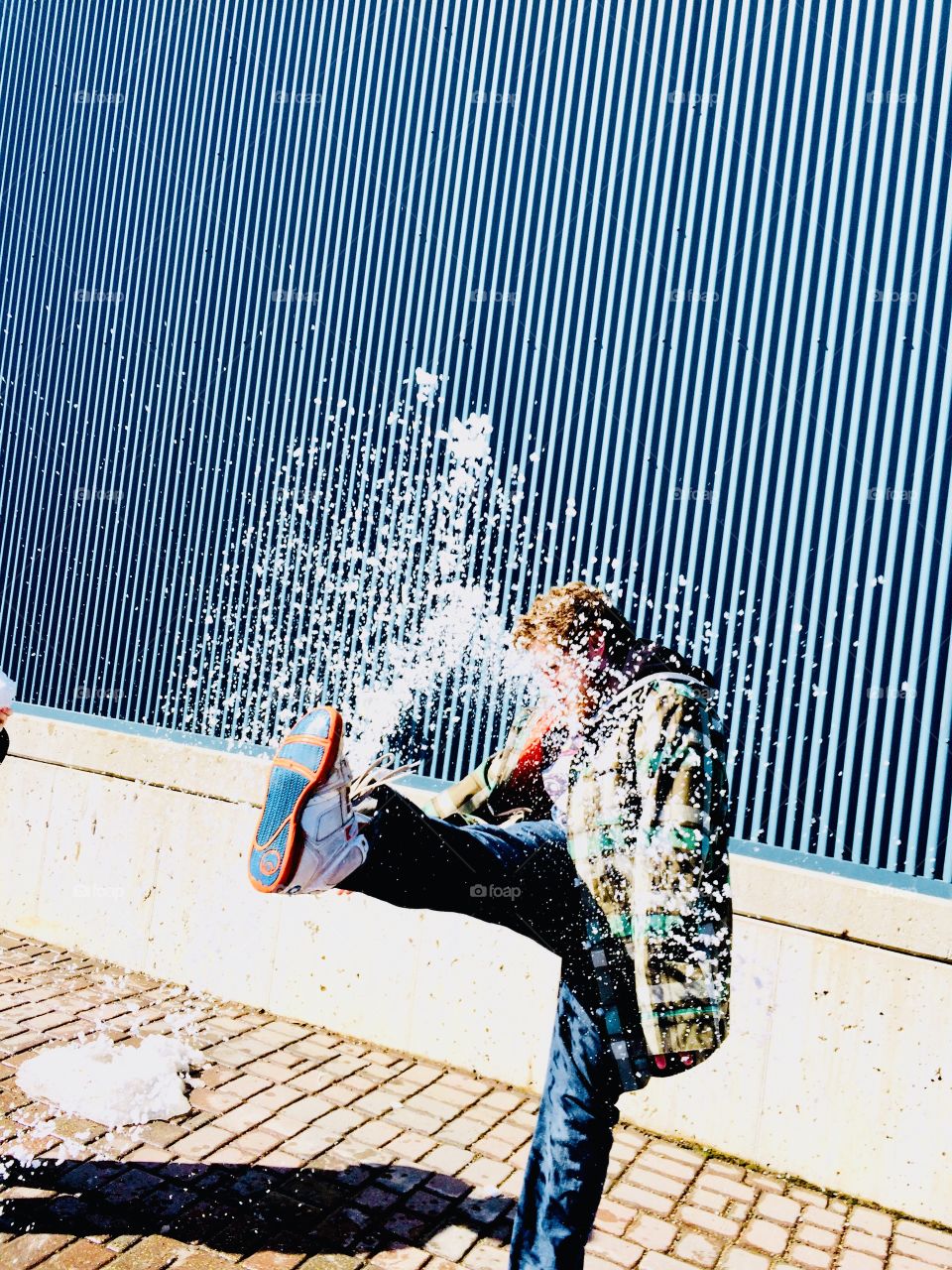 Man kicking a snowball making it fly into the air makes for a fun winter photo! 