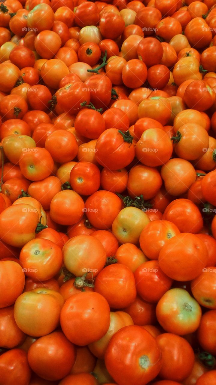 Abundence of round bright fresh red tomatoes in market