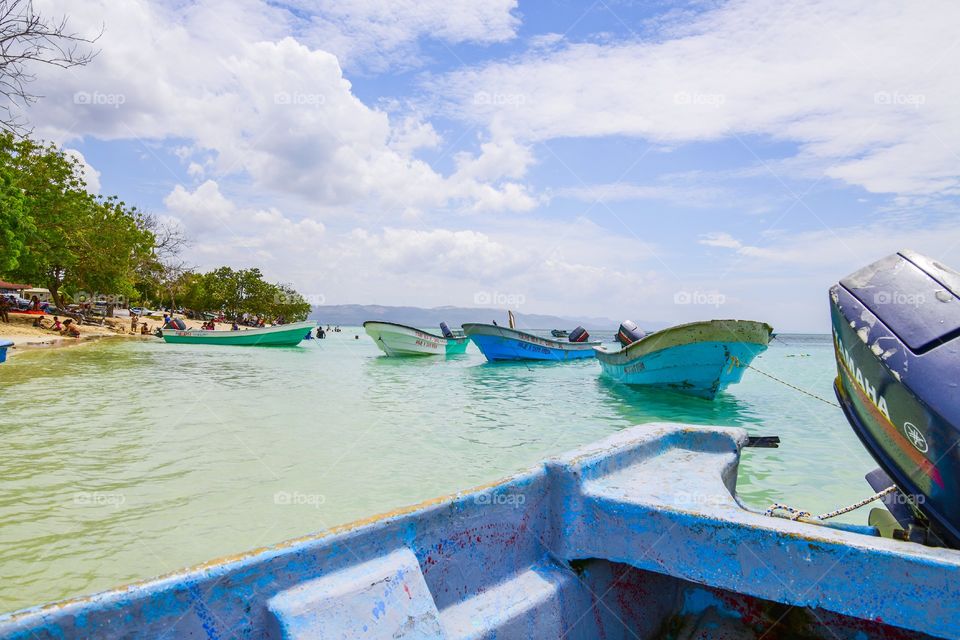 blue and green boats moored at beach in tropics