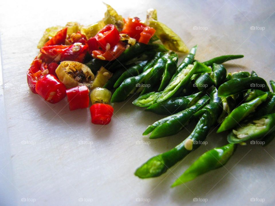 Close-up of sliced ​​green and red chilies placed on a cutting board in high angle view