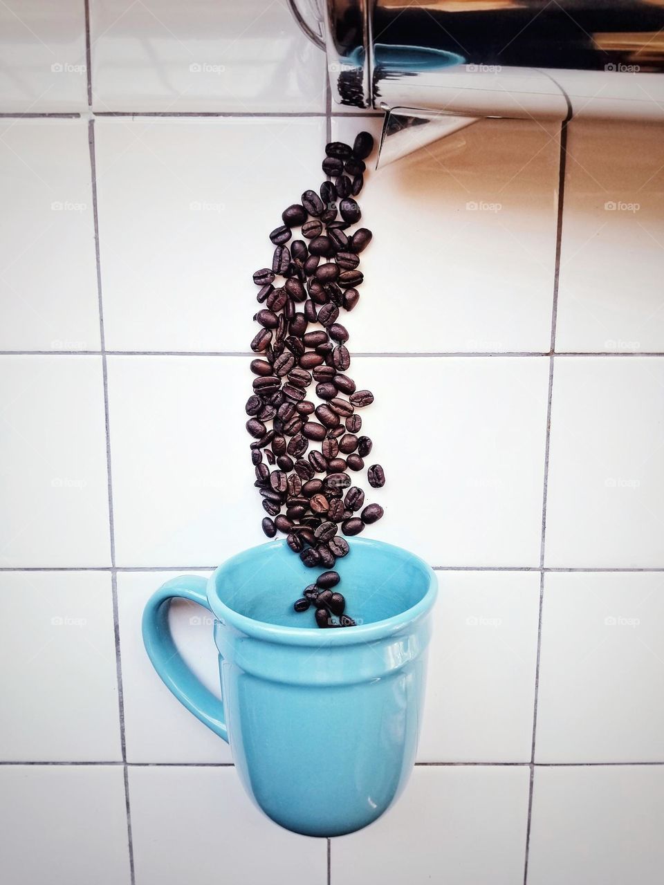Whole Coffee Beans being poured into a mug from a coffee pot from above