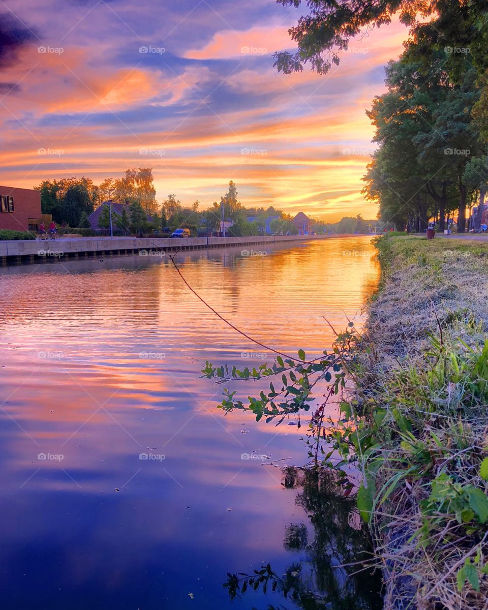 Purple sunset or sunrise sky reflected in the water of a river running through a Countryside landscape 