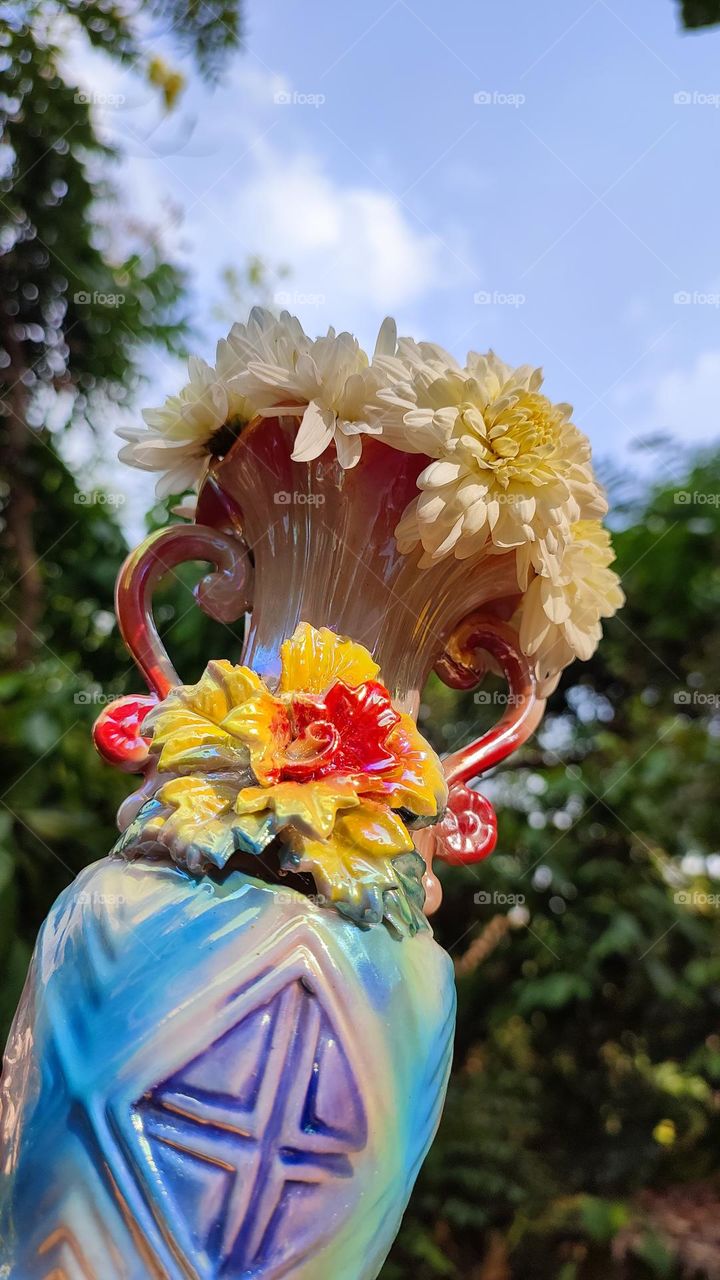 Beautiful white flowers in a colourful flowerpot with a flower sculpture