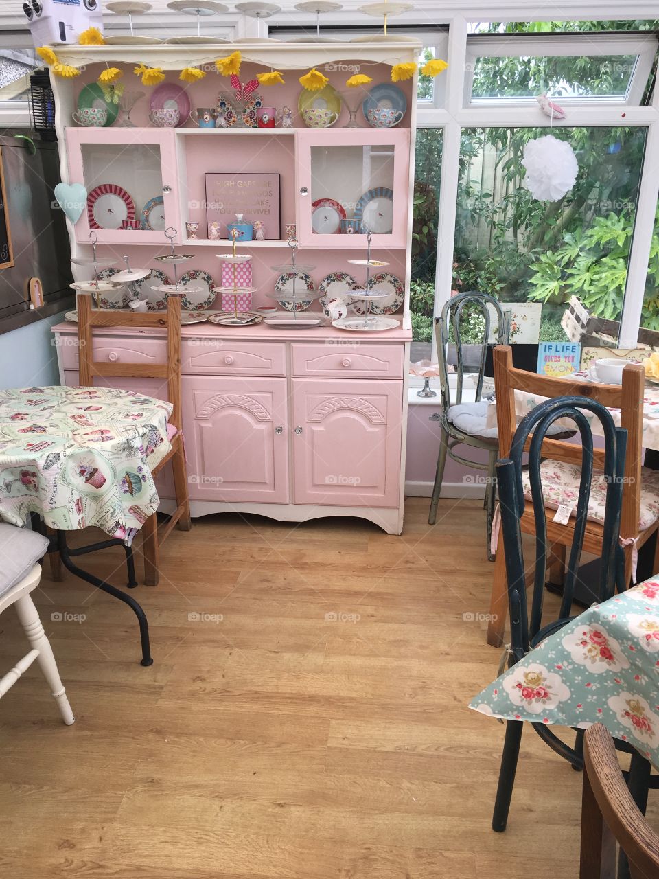 Pretty pink dresser with tables and chairs in a vintage chic style inside a tearoom in summer 
