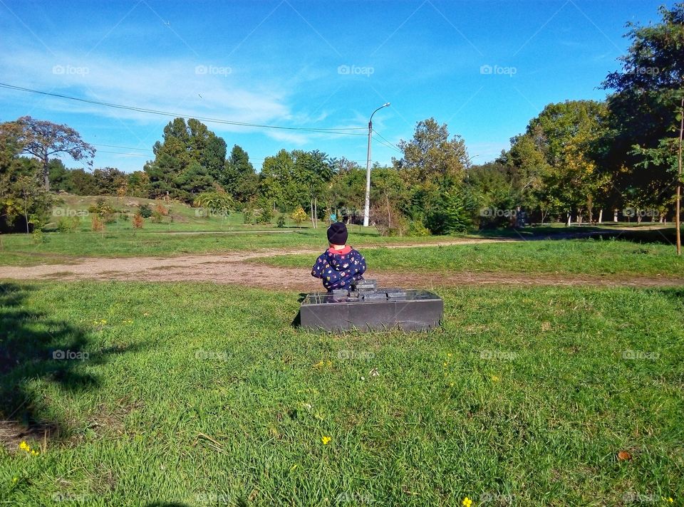 the boy is sitting on the stove in the park мальчик сидит на плите в парке