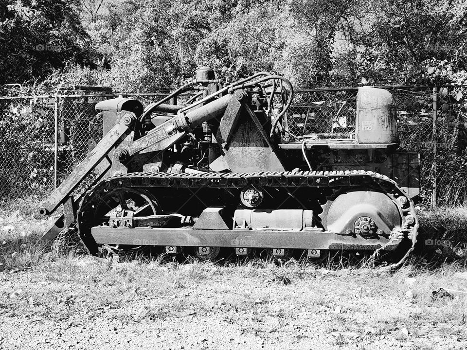 A derelict tractor sits in a field seemingly abandoned