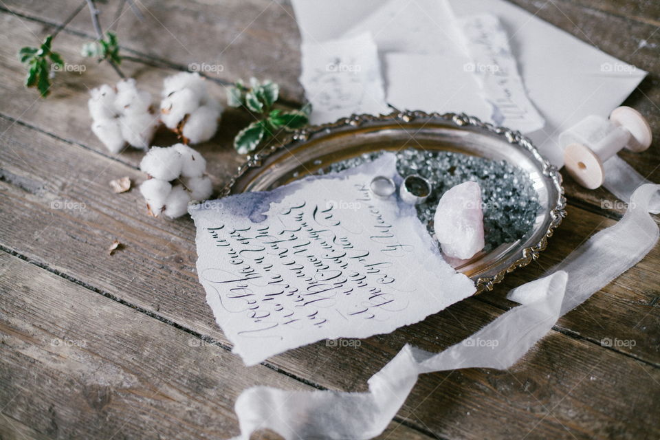 Graphic arts of beautiful wedding calligraphy cards and silver plate with two wedding ring on wood background.