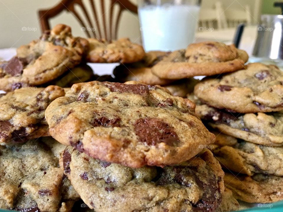 Plate of homemade chocolate chip cookies alongside a cold glass of bubbly milk