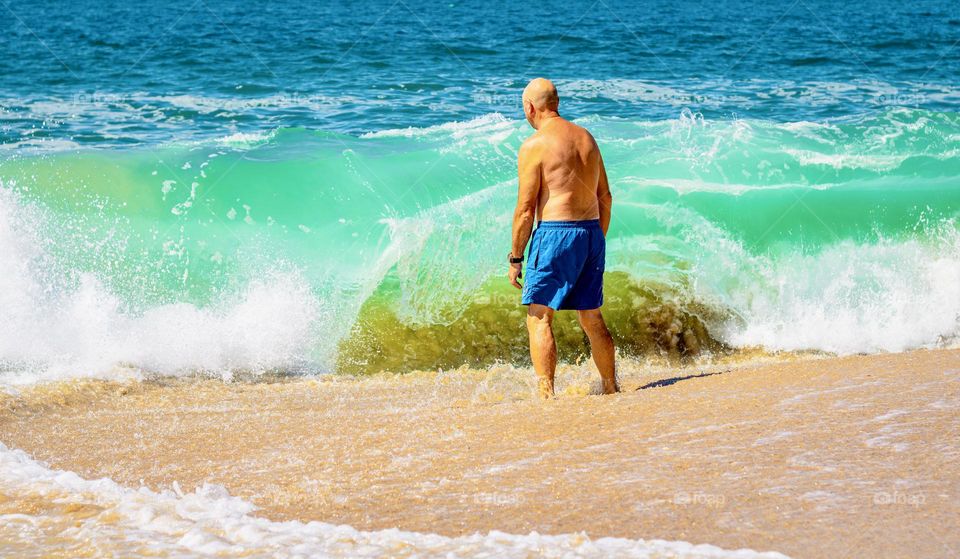 Tanned man on a sandy beach with Atlantic blue waves