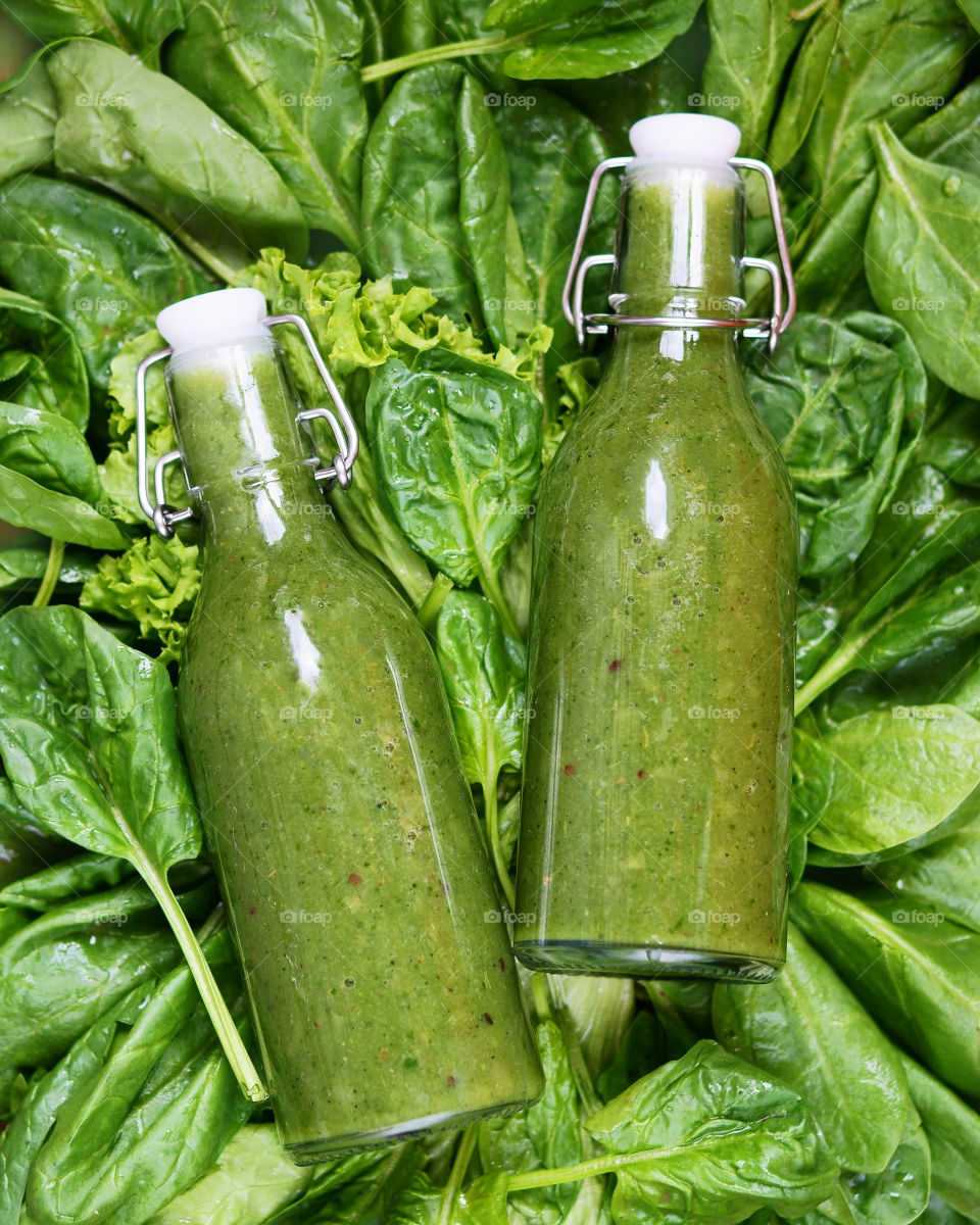 green spinach smoothie in glass bottles