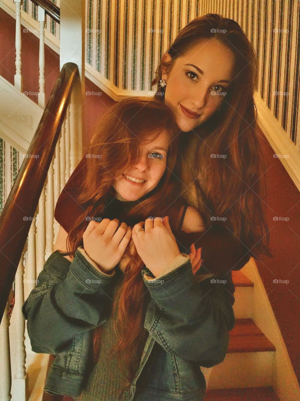 two beautiful young girls posing in a hugging position on a staircase