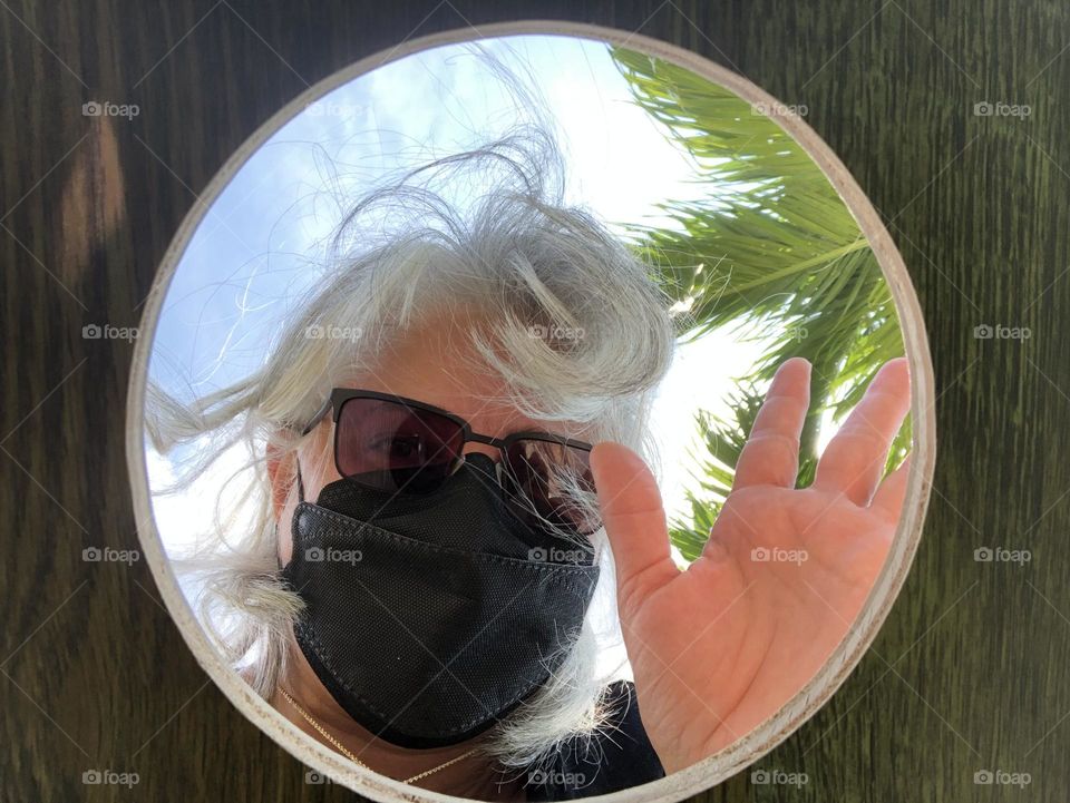 From the ground up camera under corn hole game board looking up at player through the hole