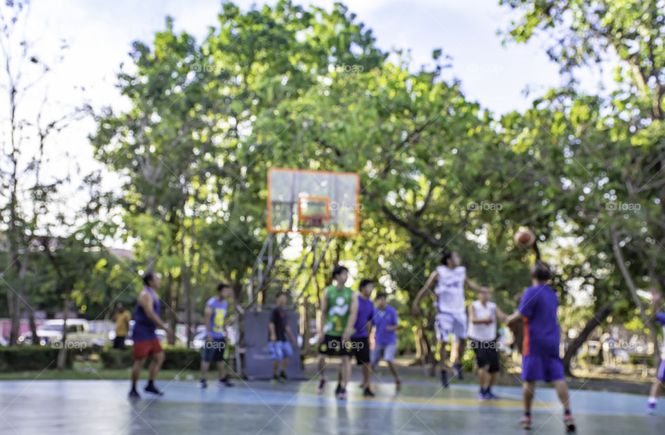 Blurry image of elderly men and teens playing basketball in the morning at BangYai Park , Nonthaburi in Thailand.