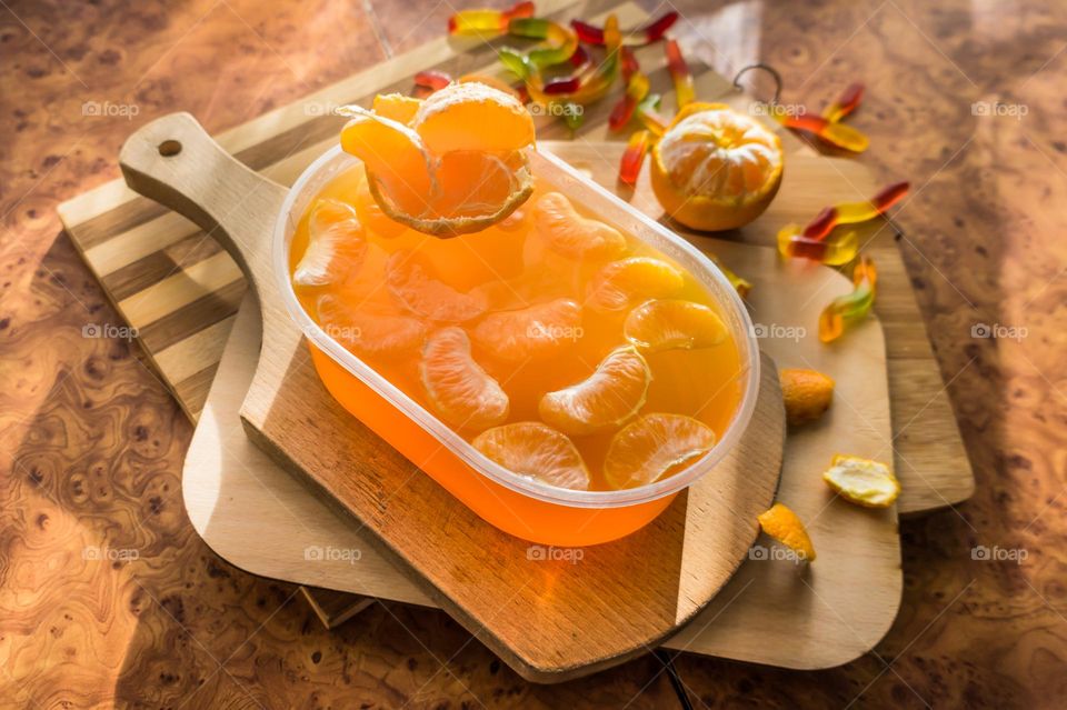 Delicious orange jelly with tangerine slices in a container and jelly worms.