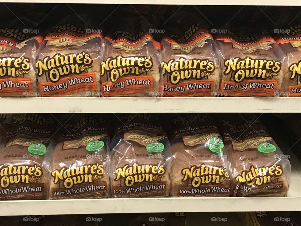 Two rows of wheat bread at the supermarket. There are two kinds of wheat breads indicated here-honey wheat and whole wheat. Take your pick.
