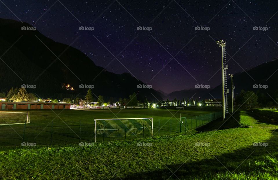 Football field at night with a sky full of stars above