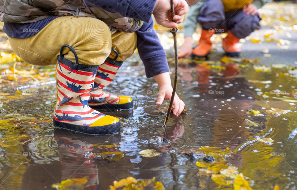 Little toddler kid rubber boots in puddle