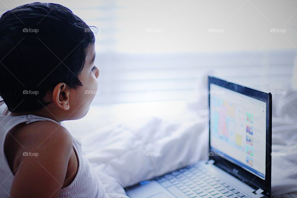 Kid using laptop and using technology while at home enjoying his favorite cartoon movie 