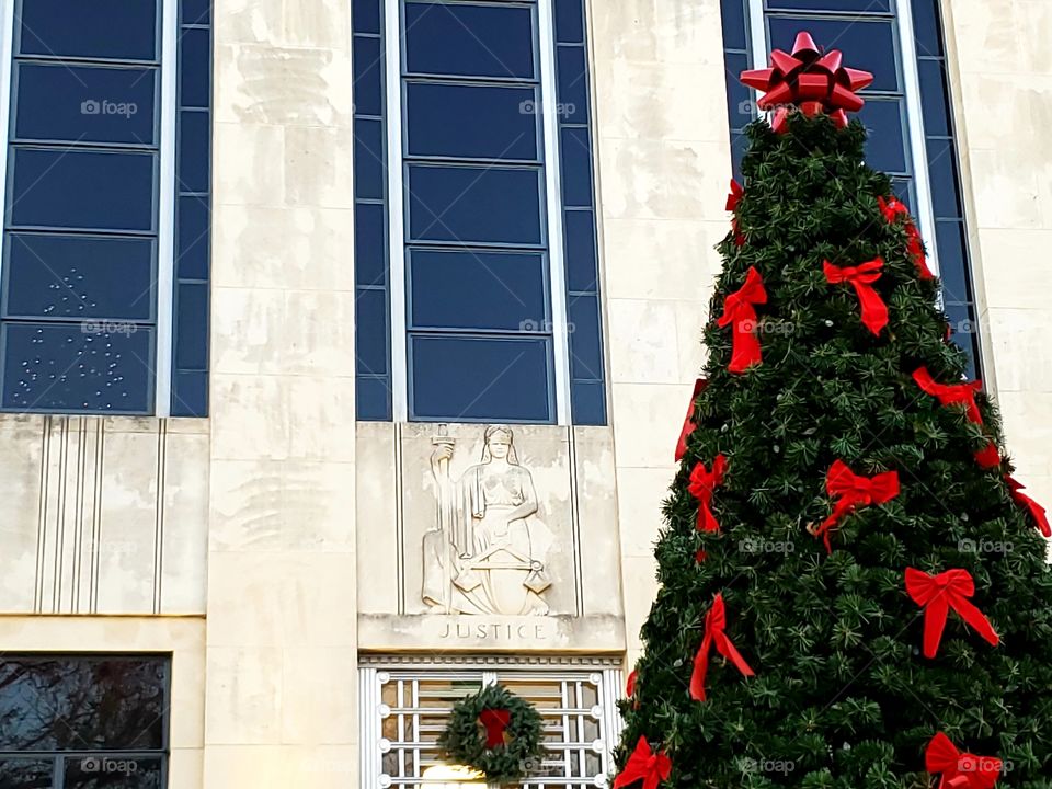 Christmas tree outside courthouse and a second Christmas tree behind one of the courthouse windows