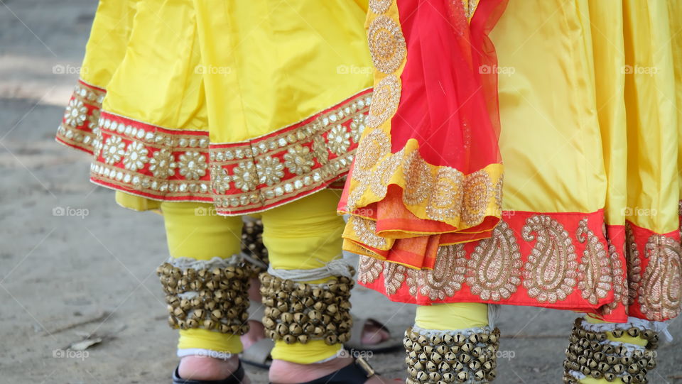 Indian performers wearing brightly colored clothes and dancing bell anklets.
