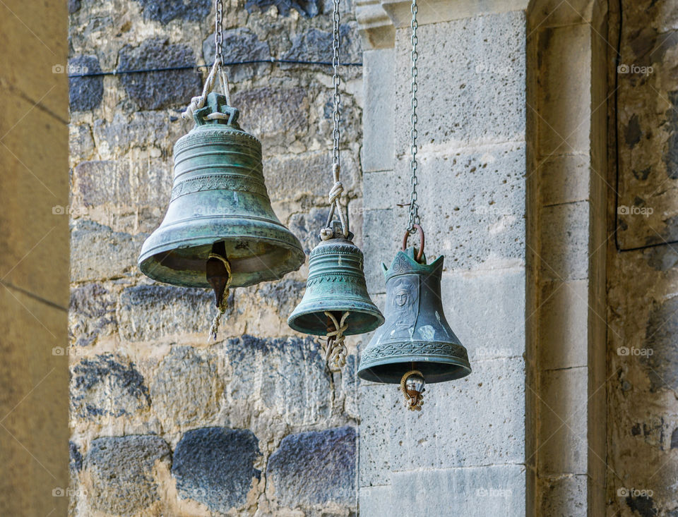 tree church bells of small, medium and large size hanging in chains