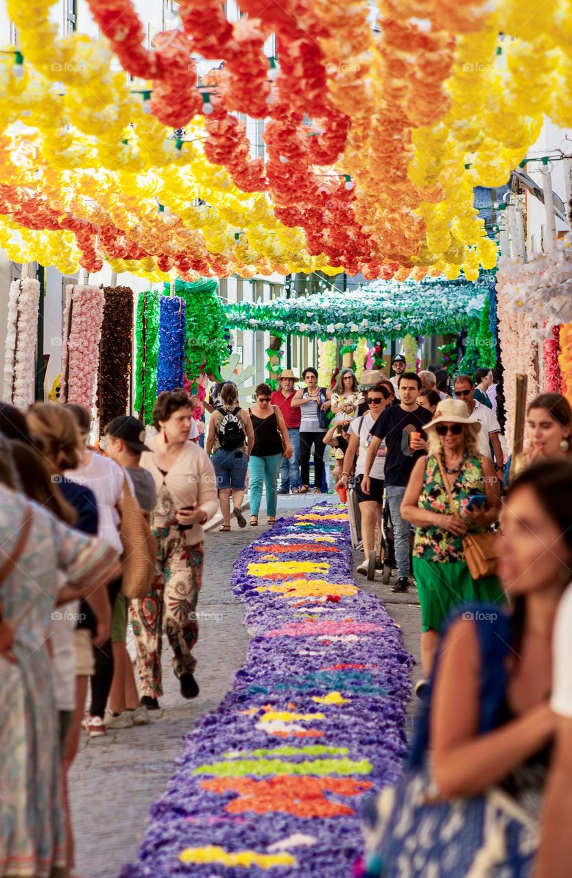 Crowds of people enjoy the streets decorated with paper flowers and displays for Festa Dos Tabuleiros in Tomar, Portugal 2023.