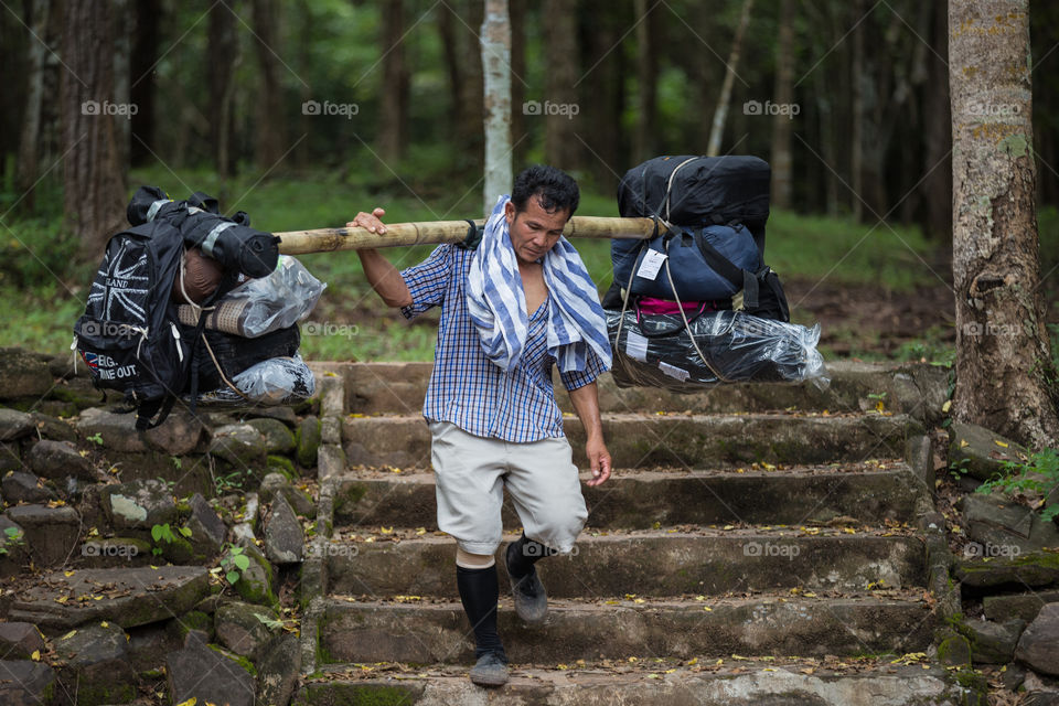 Man carrying a lot of bag of the tourist on their shoulder in Phu Kradueng national park Thailand 