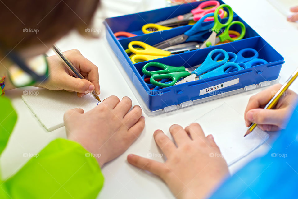 Children writing stories and  drawing before cutting their characters. Children creativity