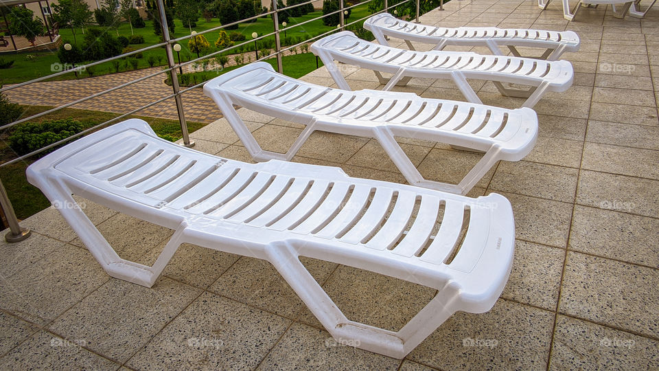 Row of free sunbeds at the swimming pool in a touristic resort.