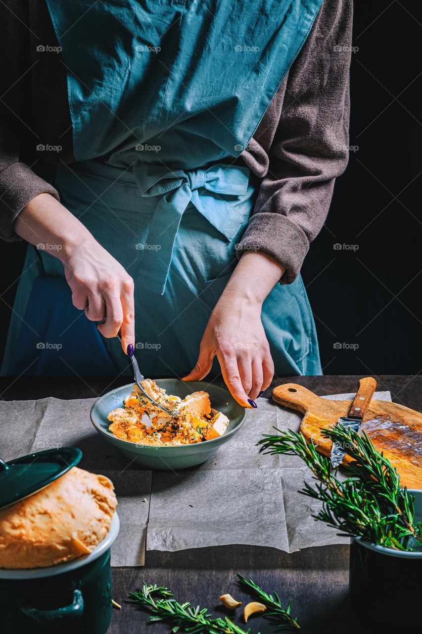 Women's hands, flour and dough. Levitation in a frame of dough and flour. A woman in an apron is preparing dough for home baking. Rustic style photo. Wooden table, wheat ears and flou.Emotional photo