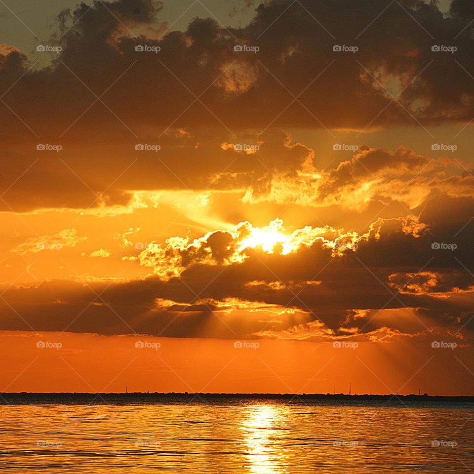 Mesmerizing sunset over the ocean with golden colored sky and floating puffy clouds. over an open waterway. The effects of weather on our moods and emotions depends on our behavior and on how we think