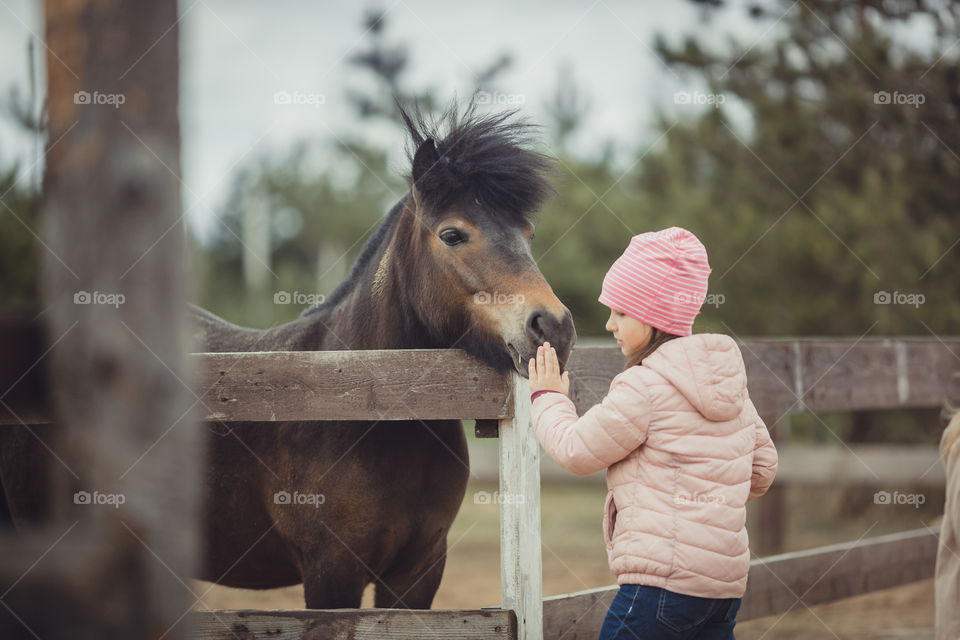 Little girl with pony, outdoor portrait 