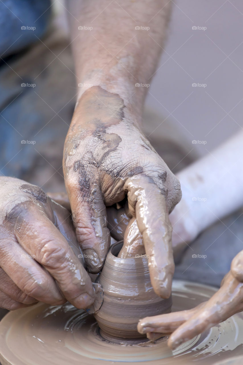 Two people making pot on pottery wheel