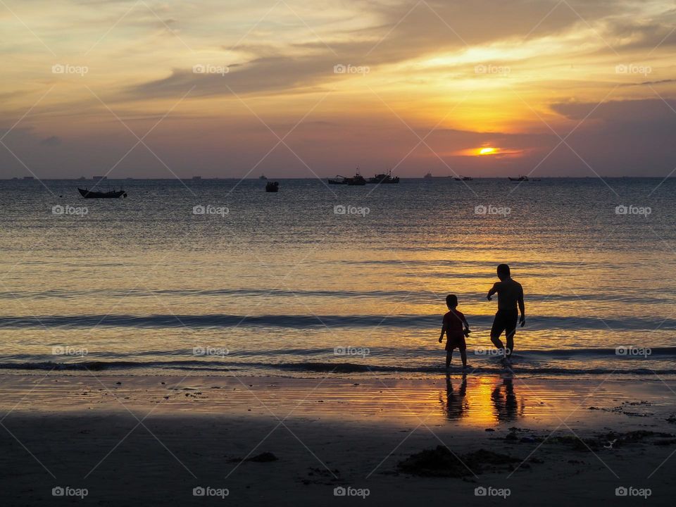 silhouette of father and child in sunset on the beach