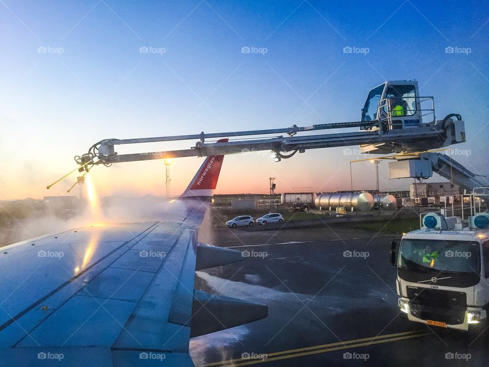 An airplane from Norwegian on Copenhagen Airport is being de-iced. De-icing is defined as removal of snow, ice or frost from a surface. Anti-icing is understood to be the application of chemicals that not only de-ice, but also remain on a surface and continue to delay the reformation of ice for a certain period of time, or prevent adhesion of ice to make mechanical removal easier.