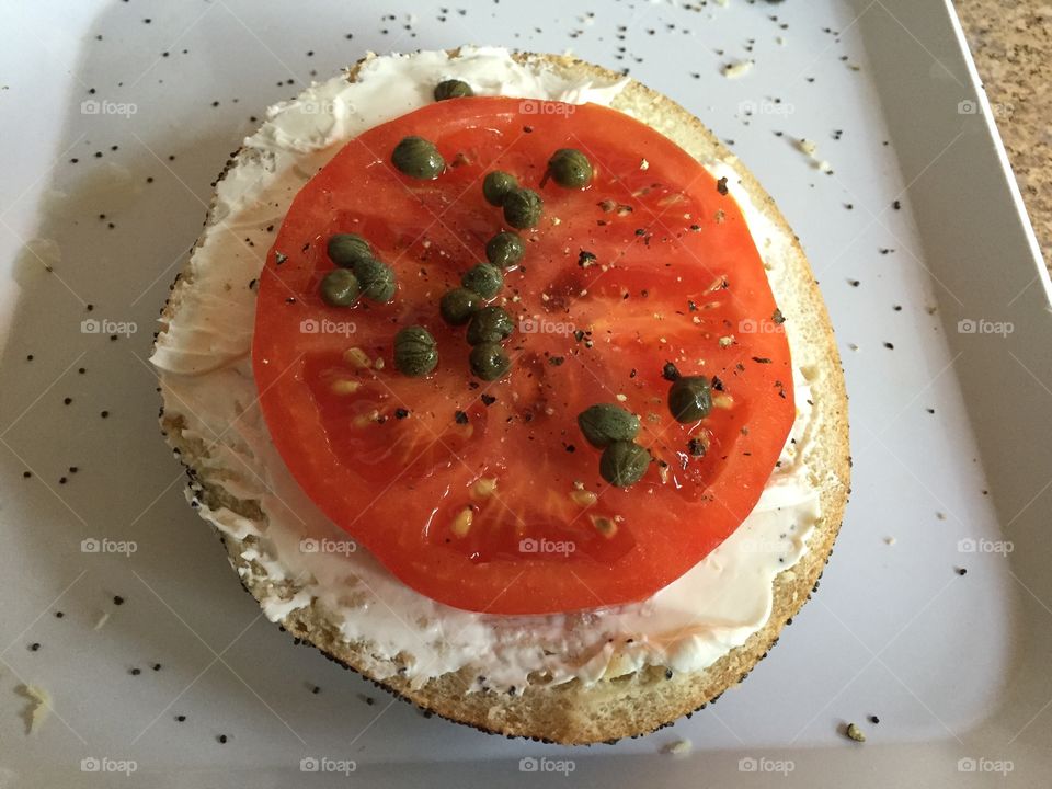 Bagel, cream cheese, tomato and capers. 